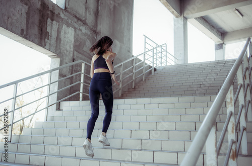 Fit woman runner runs up the stairs