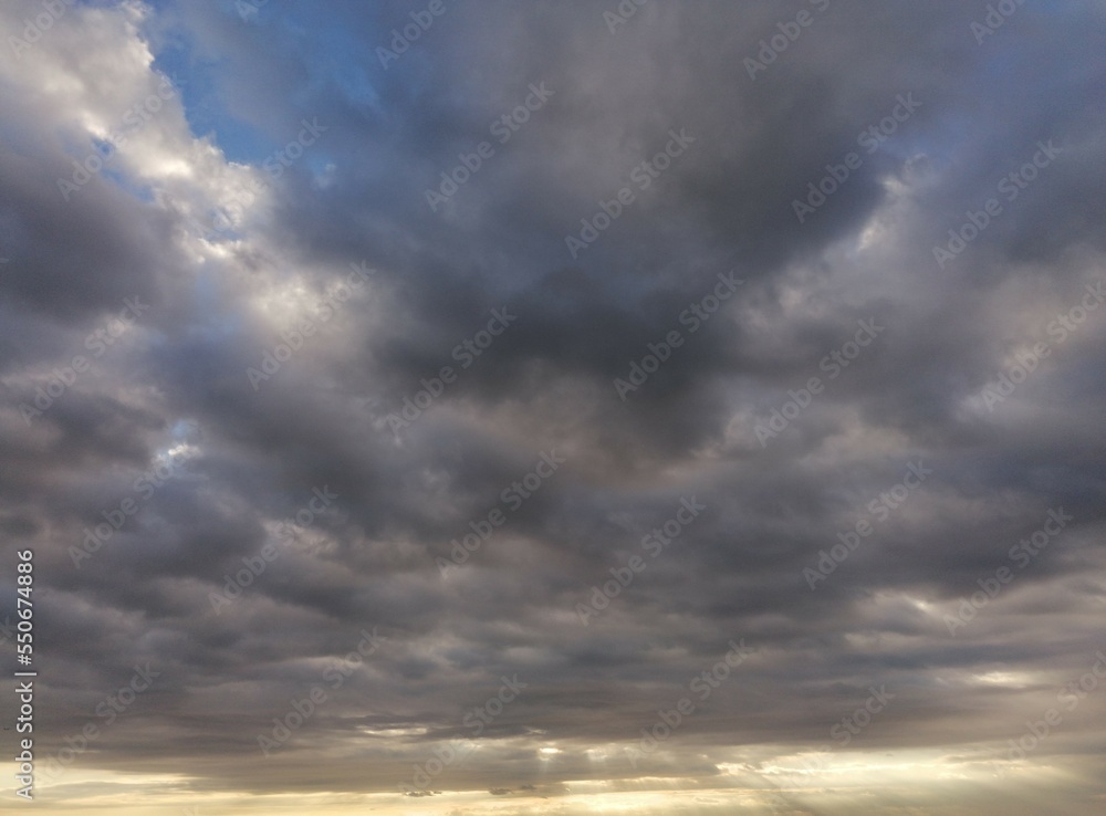 Fondo natural con multitud de nubes en tonos azules y grises, con rayo de sol filtrados