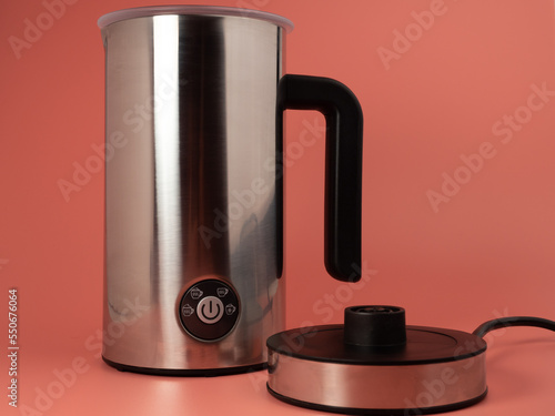 Automatic milk foam maker. Stainless steel milk frother with buttons and power cord on a pink background. photo