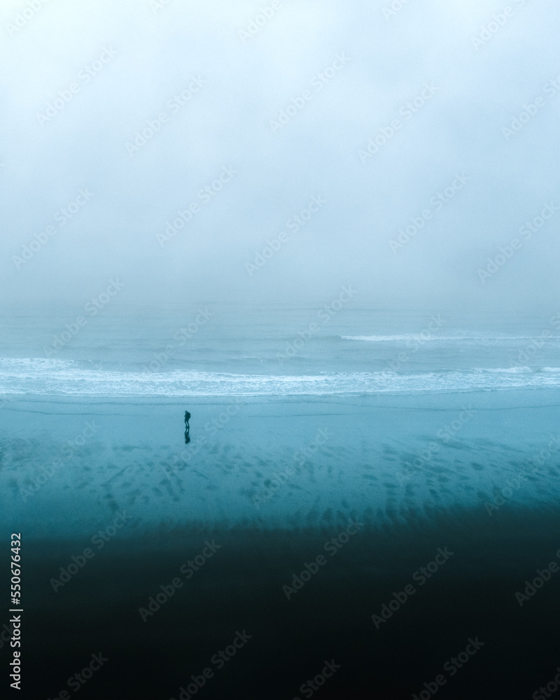 person watching the waves in Iceland on a stormy and cloudy day person watching the waves in Iceland on a stormy and cloudy day