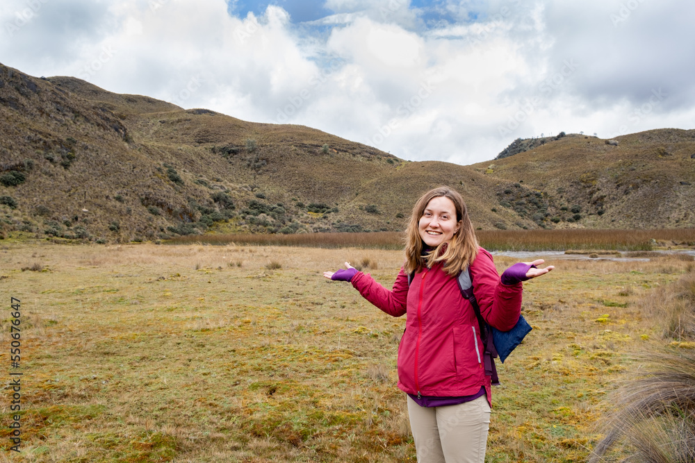 A smiley female hiker lost in the Andean paramo shrugging her shoulders in Cajas National Park in the highlands of Ecuador, tropical Andes.