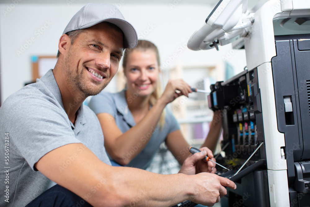Fototapeta premium couple of workers fixing a printer