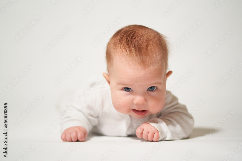 portrait of an infant lying on his back with a sly emotion on a white background portrait of an infant lying on his back with a sly emotion on a white background
