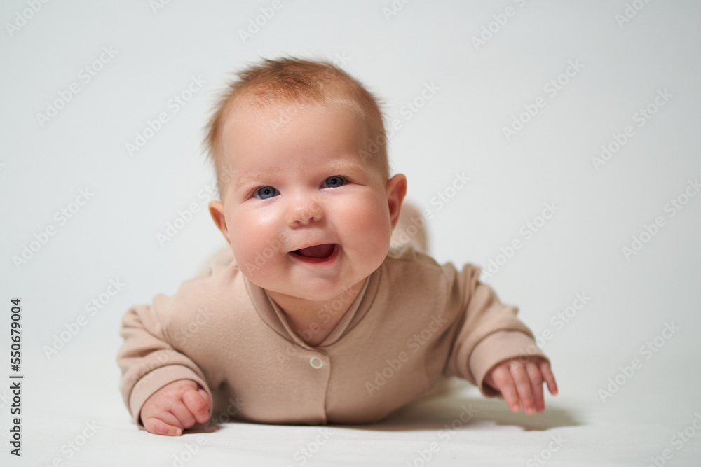 portrait of an infant lying with a cheerful emotion on a white background portrait of an infant lying with a cheerful emotion on a white background