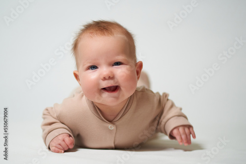 portrait of an infant lying with a cheerful emotion on a white background