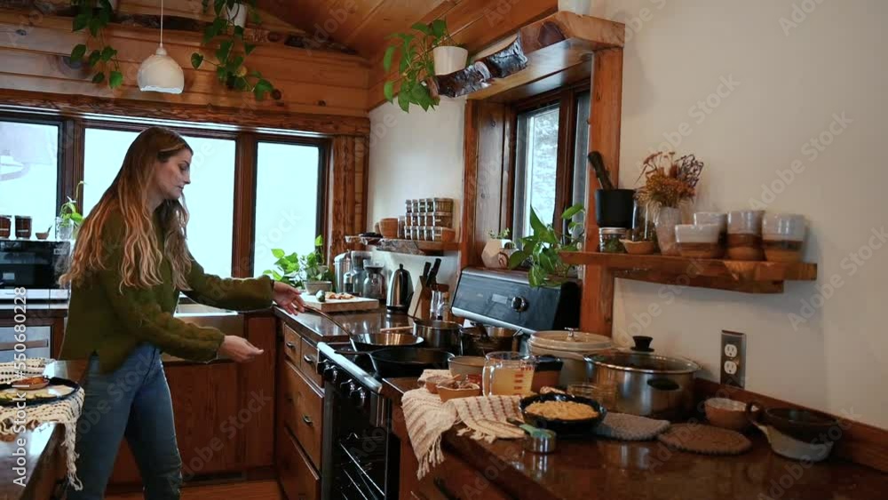 A snowy day at home cooking in a mountain cabin - woman cooking a delicious healthy vegetarian meal with warm winter cabin vibes