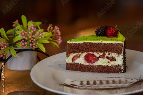 Piece of chocolate cake with icing and fresh berries on wooden background. Chocolate cake with strawberries on a wooden table close-up. Food. 