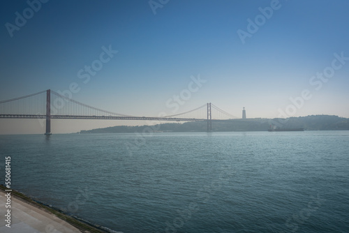 Fototapeta Naklejka Na Ścianę i Meble -  Tagus River (Rio Tejo) with 25 de Abril Bridge and Sanctuary of Christ the King on background  - Lisbon, Portugal