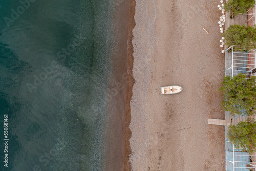 Aerial view of a small wooden boat on land beside turquoise water of Mediterranean Sea