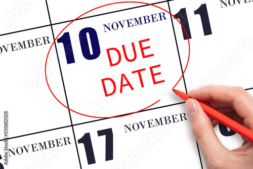10th day of November. Hand writing text DUE DATE on calendar date November 10 and circling it. Payment due date. Business concept. Autumn month, day of the year concept.