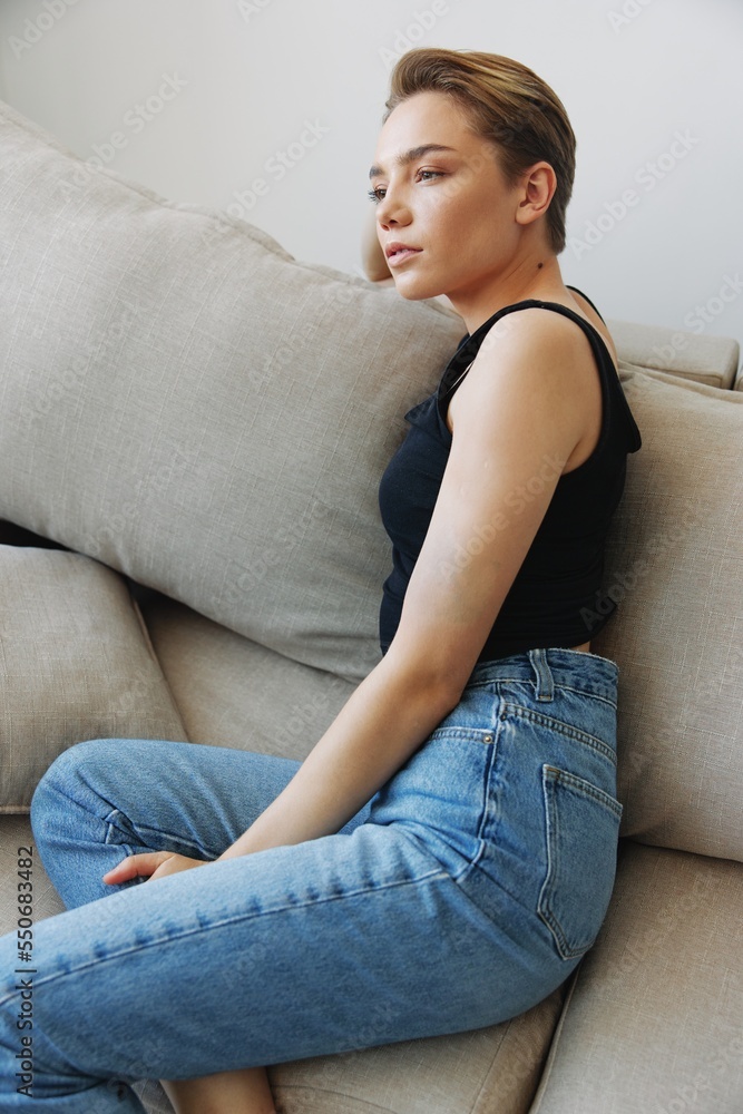 Young woman with short haircut hair having fun at home on the couch smile and happiness, vacation at home, natural posing without filters, free copy space Young woman with short haircut hair having fun at home on the couch smile and happiness, vacation at home, natural posing without filters, free copy space