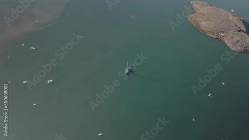 Aerial view of a sailing boat navigating along the fjords in Sermersooq, Greenland. photo