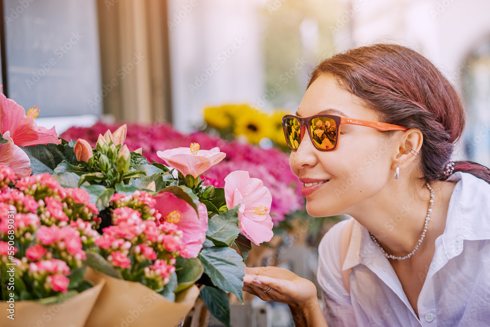 Naklejka premium A girl buyer and a client choose bouquets and flowers in pots at market and florist shop on a city street