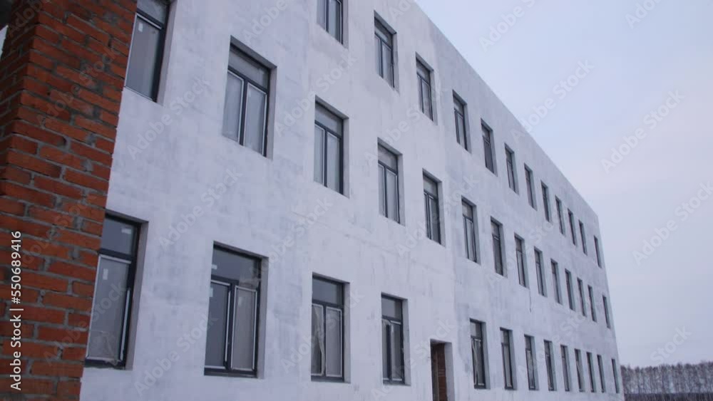 Concrete facade with windows of building at construction site on gloomy day. Future medical center in city block Concrete facade with windows of building at construction site on gloomy day. Future medical center in city block