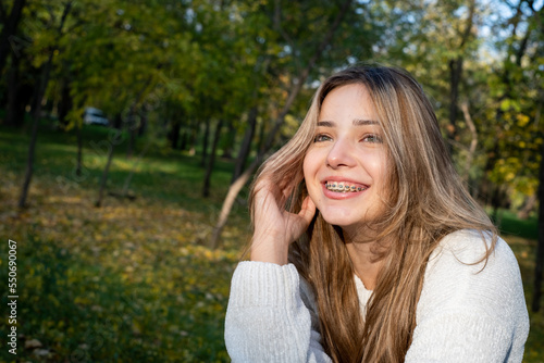 teenage girl with braces sitting in the park smiling