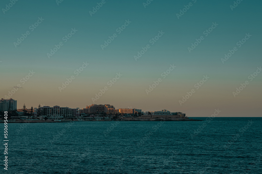 Beautiful panorama of bulidings around sant julian bay on malta on autumn evening. Beautiful waterline of hotels on malta.