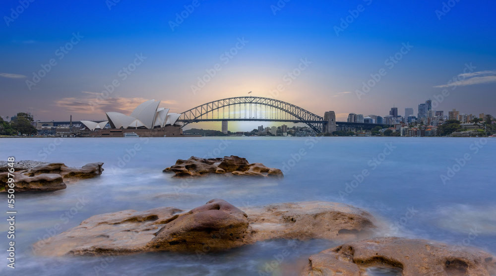 Naklejka premium Sydney Harbour Australia at Sunset with the turquoise colours of the bay and high rise offices of the City in the background