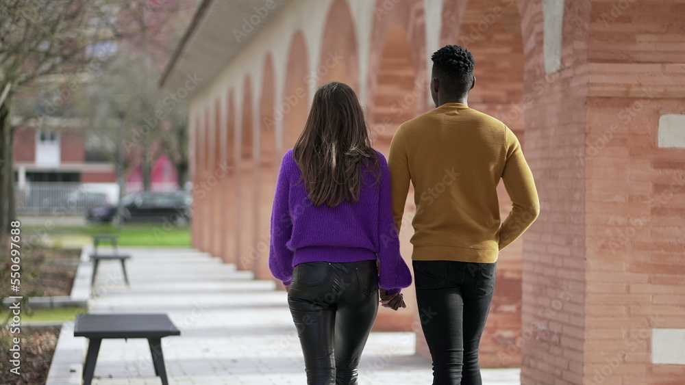 Young interracial couple walking together outside holding hands