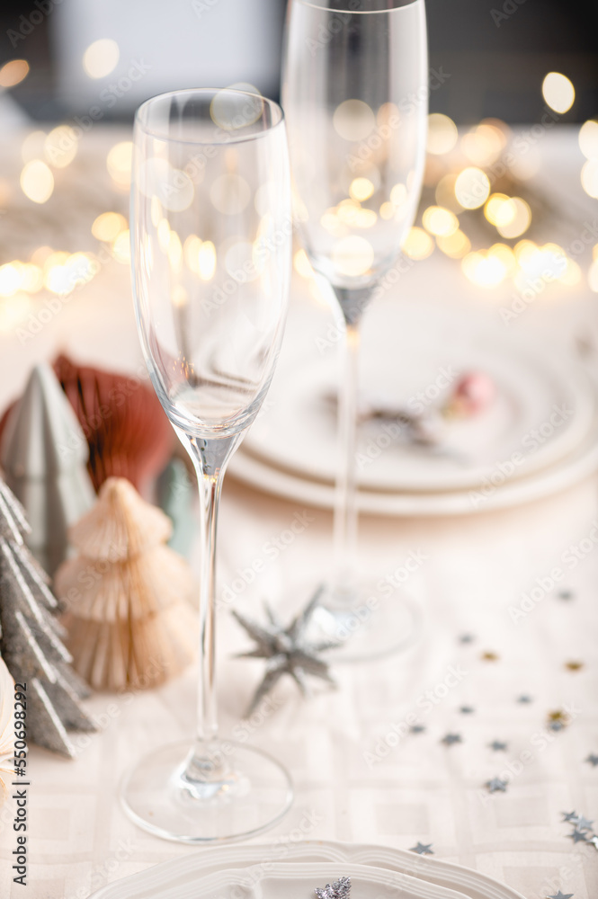 Xmas table settings in white and pink colors with trendy paper christmas trees on background, empty plates and glasses ready for festive dinner and party Xmas table settings in white and pink colors with trendy paper christmas trees on background, empty plates and glasses ready for festive dinner and party