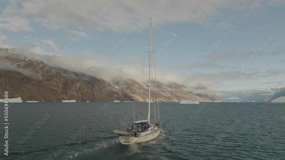 Sermersooq, Greenland - 17 November 2022: Aerial view of a sailing boat in a bay at sunset along the coast Sermersooq, Greenland - 17 November 2022: Aerial view of a sailing boat in a bay at sunset along the coast