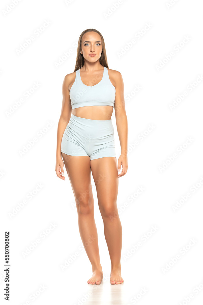 young barefoot sports woman with long hair in a shorts and top on a white background young barefoot sports woman with long hair in a shorts and top on a white background