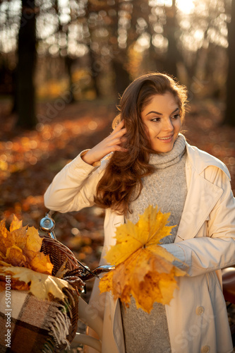 Young woman looking away with bicycle in autumn forest