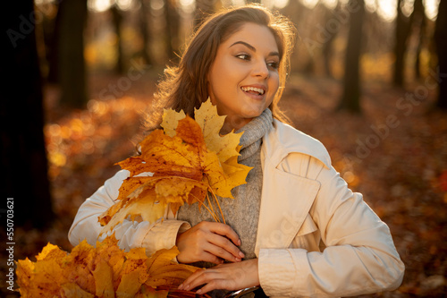 Cute smiley woman holding autumn leafs in the nature