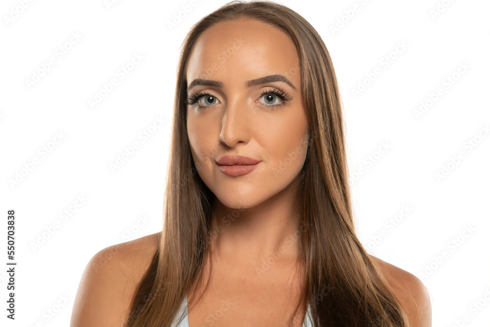 Fototapeta premium beautiful young serious women with makeup and long hair on a white studio background.