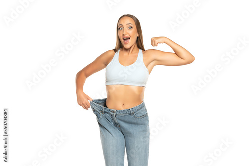 Successful weight loss, beautiful woman with too large jeans after effective diet on a white background photo