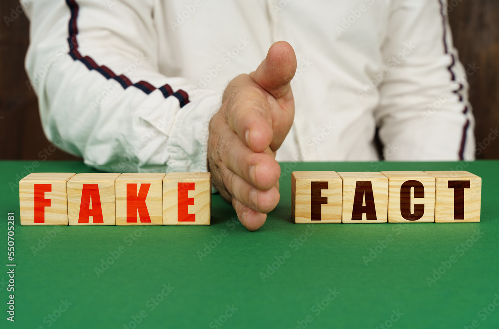 Obraz premium A man separates the cubes with the inscription - FAKE or FACT