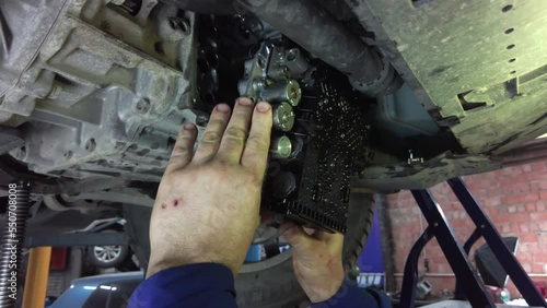 the master in the car service takes out with his hands a spare part repair mechatronics DSG bottom view. High quality 4k footage