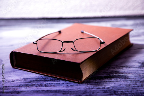 book and optic glasses on wooden background