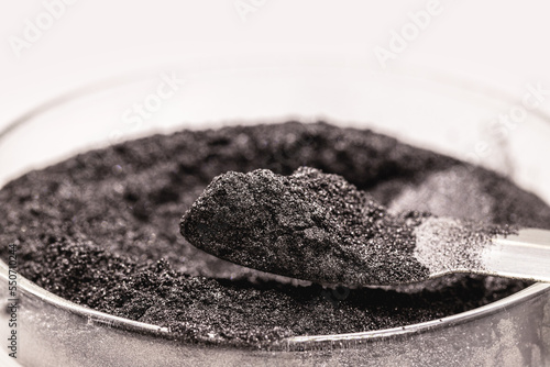 black pigment, powder for industrial or cosmetic use, isolated white background, in petri dish photo