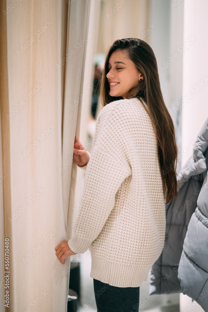 A girl trying on a white sweater in a store. A girl trying on a white sweater in a store.