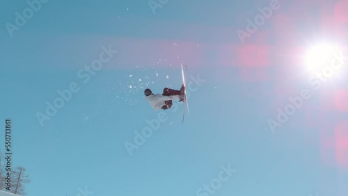 VOGEL, BOHINJ, JULIAN ALPS, SLOVENIA, MARCH 2022: SLOW MOTION: Male skier jumping big air kicker at snow park in snowy ski area. Extreme skier double rotating through the air and performing grab trick photo