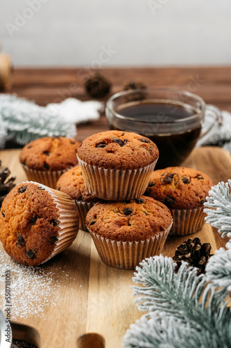 
muffins with chocolate on a wooden stand, powdered sugar, cones, Christmas tree branches nearby