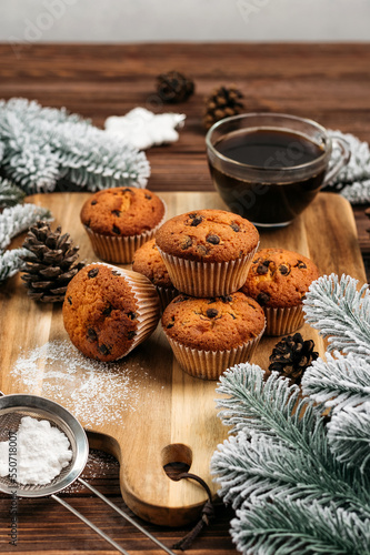 
muffins with chocolate on a wooden stand, powdered sugar, cones, Christmas tree branches nearby