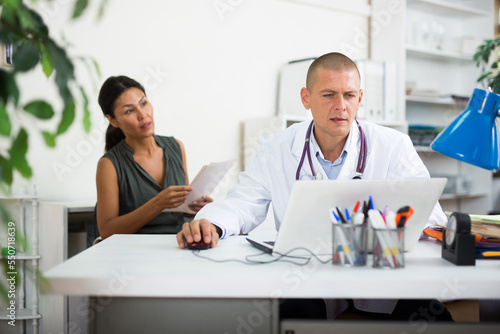 Middle aged asian female patient visits young doctor in office at the hospital