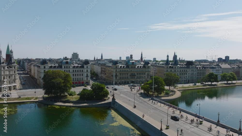 Sunny day in city, aerial view of traffic on bridge over lake, crossroad and street lined by rows of buildings. Copenhagen, Denmark Sunny day in city, aerial view of traffic on bridge over lake, crossroad and street lined by rows of buildings. Copenhagen, Denmark