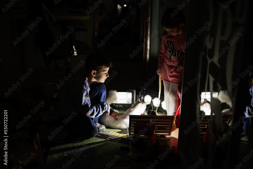 Kids playing with cat at home during a blackout using alternative lighting.