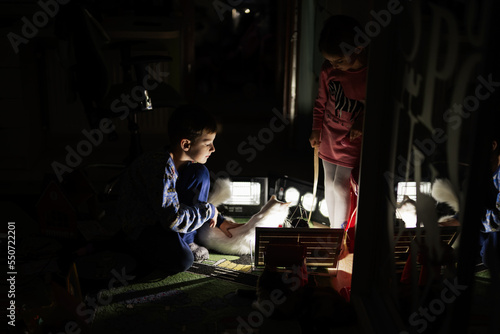 Kids playing with cat at home during a blackout using alternative lighting.