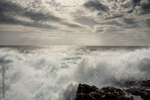 Powerful ocean wave hits rough stone coast of Aran Island, county Galway, Ireland. Rough nature scene. Water splash. Power of nature. Cloudy sky. Irish landscape. Popular tourist area photo