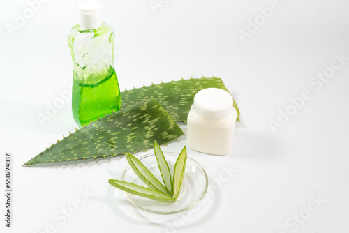 pieces of Aloe Vera leaf, glass container, plastic and detergent bottle on a table