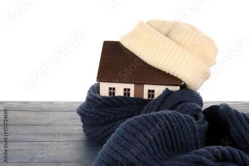 House model with hat and scarf on table against white background. Heating concept