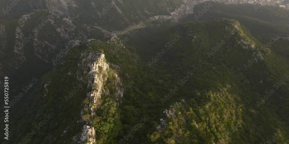 Aerial folllowing the ridge of a green hill until reaching a massive cliff, during sunset golden hour Aerial folllowing the ridge of a green hill until reaching a massive cliff, during sunset golden hour