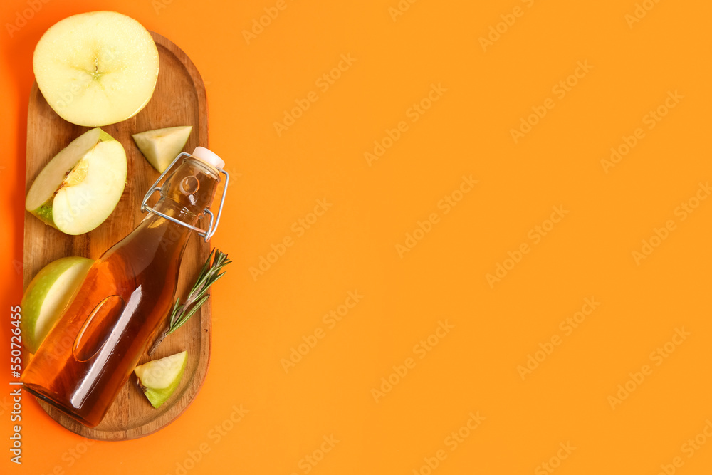 Wooden board with cut ripe apple and bottle of juice on color background