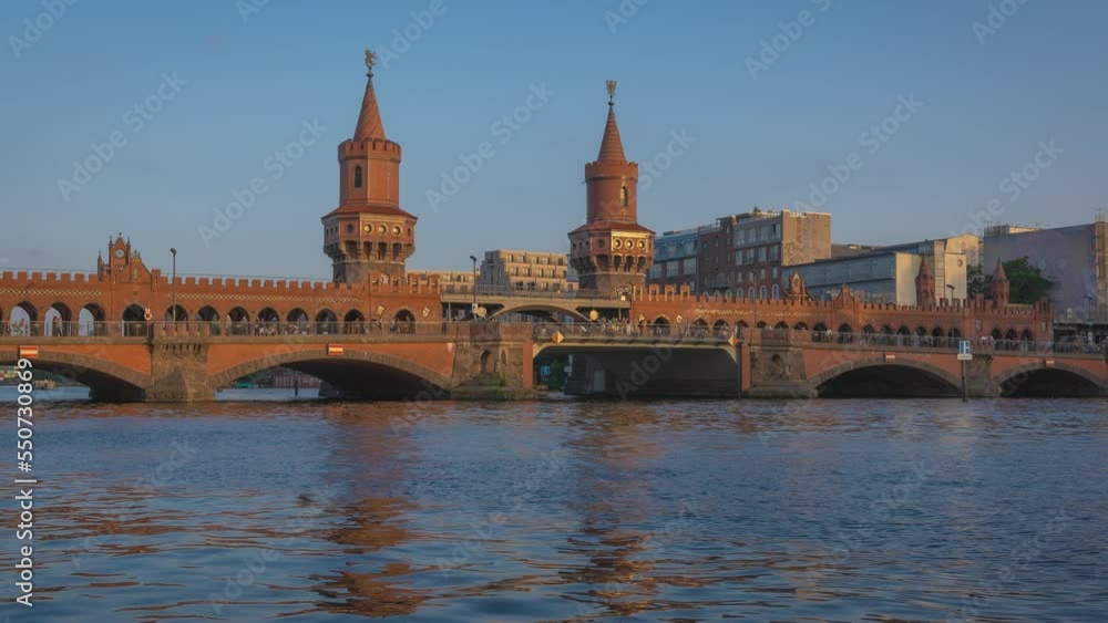 Evening Berlin time lapse. Oberbaumbrücke (Oberbaum Bridge) over Spree River that links Kreuzberg and Friedrichshain districts, Kreuzberg district. A subway train passes over the bridge. Evening Berlin time lapse. Oberbaumbrücke (Oberbaum Bridge) over Spree River that links Kreuzberg and Friedrichshain districts, Kreuzberg district. A subway train passes over the bridge.
