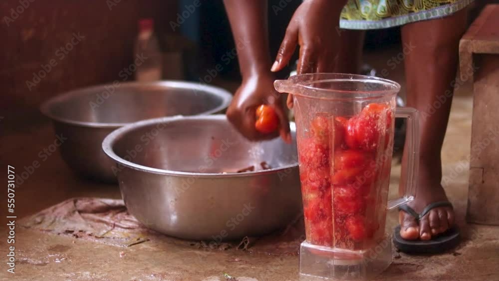 African Woman washing tomatoes into blender. Woman preparing to blend vegetables in the kitchen. African Woman washing tomatoes into blender. Woman preparing to blend vegetables in the kitchen.