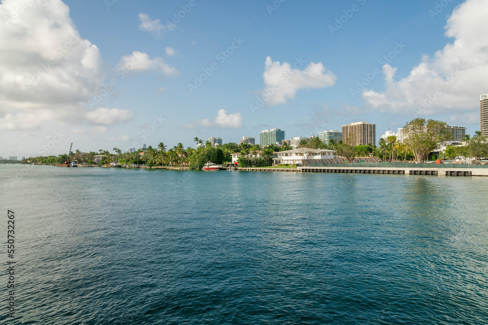 Views of buildings across the ocean under the calm sky with fluffy white clouds- Miami bay, Florida