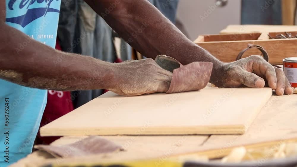 Carpenter using sandpaper to smoothen surface of a wood for furniture works Carpenter using sandpaper to smoothen surface of a wood for furniture works